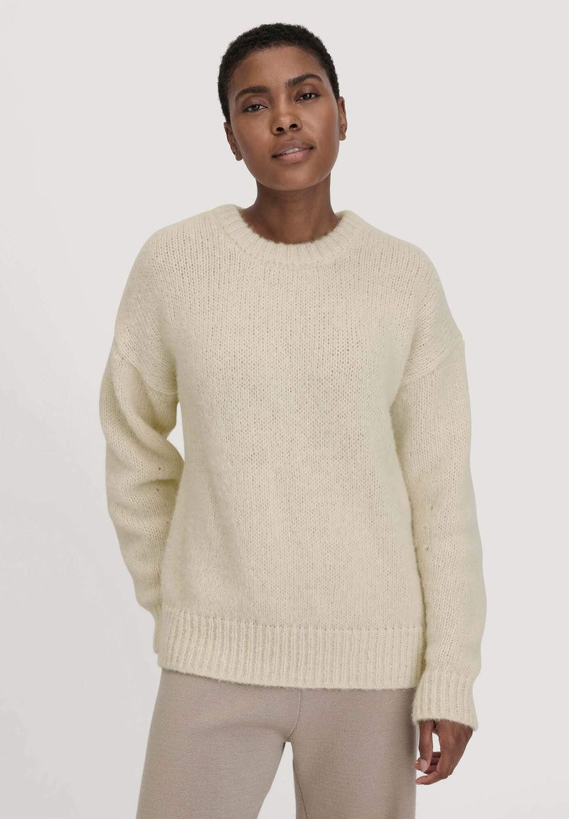 Gebreide crèmekleurige trui met een ronde halslijn, verlaagde schouders en geribbelde cuffs. Zachte textuur met een losse pasvorm en een licht oversized silhouet.