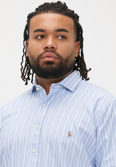 Camisa de botões às riscas azul claro feita de algodão. Apresenta uma gola clássica e um pequeno logótipo bordado no peito esquerdo.
