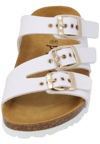 White slide sandal with three adjustable straps featuring gold buckles. Cork footbed and textured rubber sole with a light-colored edge.