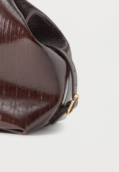 Σκούρα καφέ δερμάτινη τσάντα χειρός με γυαλιστερή επιφάνεια, υφή, στρογγυλεμένο σχήμα και ρυθμιζόμενο λουράκι με μικρή χρυσή πόρπη.