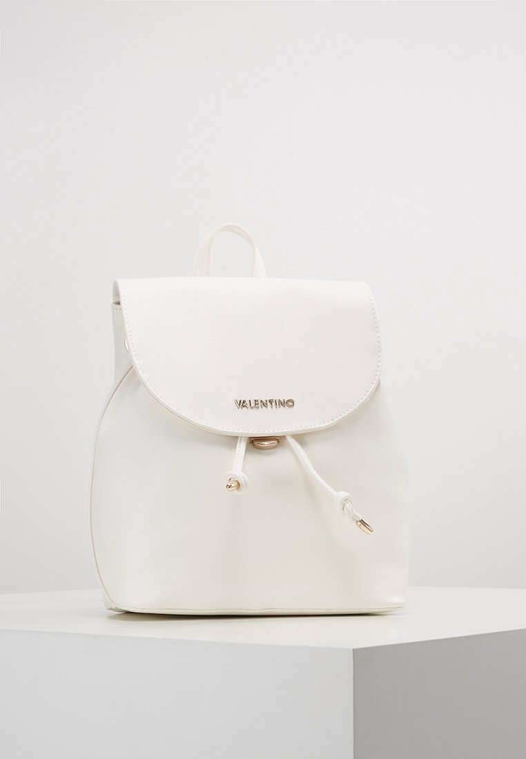 Vit fusk läder ryggsäck med rundad form, klaffstängning, guldfärgad utrustning och snörning som accent. Har en subtil präglad logotyp.