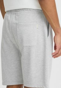 Grå bomuldsbukser med elastisk talje. Har en baglomme og et lille mærke. Glat tekstur, knælangt design.