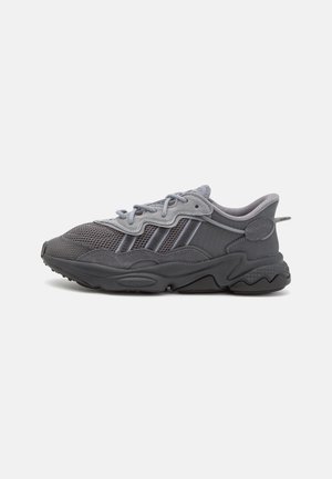 Gray and black athletic sneaker with mesh upper, wavy suede overlays, lace-up closure, and thick zigzag patterned sole.