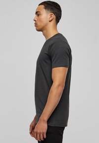 Camiseta de algodón gris oscuro con mangas cortas, cuello redondo y corte ajustado. Textura suave, sin patrones ni acentos visibles.