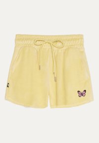 Gula sammetsshorts med elastisk midja och dragsko. Har två sidfickor och en broderad rosa fjärilsdetalj på höger sida.