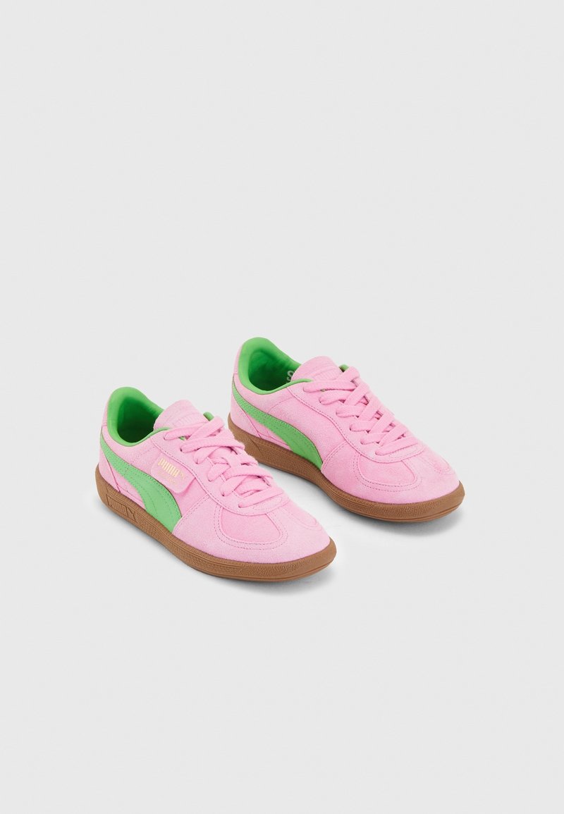 Pink suede Puma sneakers with green accents and brown rubber soles, displayed side by side on a white background.