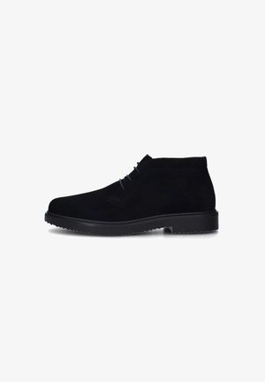 Stivaletti neri in suede con punta rotonda, caratterizzati da cuciture tono su tono, lacci minimali e una suola in gomma spessa con battistrada testurizzato.