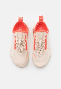 Beige ja koralli urheilukengät, joissa on neulottu päällinen, joustavat nauhat ja teksturoitu pohja. Varustettu vedettävillä nauhoilla kantapäässä.