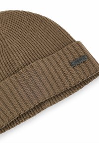 Berretto a maglia marrone con texture a coste, con risvolto e un piccolo etichetta nera dettagliata sul lato.