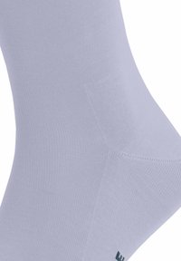 Calzino grigio chiaro realizzato in tessuto elasticizzato, con una consistenza liscia e un design a coste. Accento del logo verde alla base.