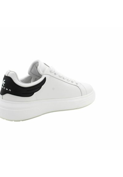 Baskets blanches avec une finition en cuir lisse, accent noir au niveau du talon, et une semelle épaisse blanche. Comprend des lacets ronds et un design minimaliste.