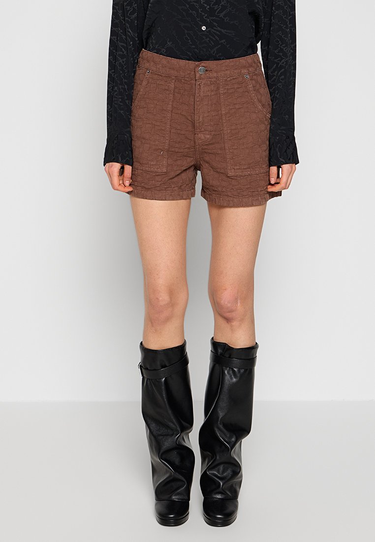 Braune, strukturierte Shorts mit zwei Fronttaschen, hoher Taille und Knopfverschluss, kombiniert mit knielangen schwarzen Lederstiefeln.