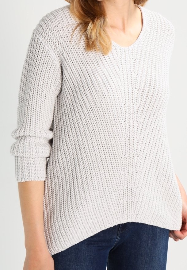 Pull en maille gris clair avec col en V, texture côtelée et manches longues, présentant un ourlet asymétrique et des coutures verticales marquées.