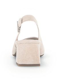 Sandal con tacco alto in suede beige, con retro chiuso, cinturino alla caviglia e tacco quadrato. La suola è di un colore marrone a contrasto.