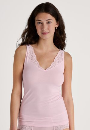 Lichtroze cami met V-hals, voorzien van zachte kanten rand langs de halslijn en schouderbanden, en een klein satijnen strikje in het midden.