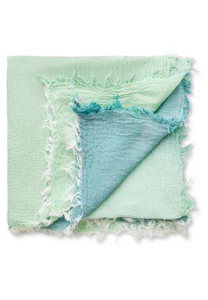 Lysegrønne og blå rynkede stoffirkanter lagdelt med frynsede kanter på en hvid baggrund.