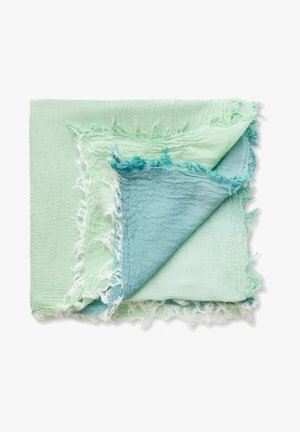 Lichtgroene en blauwe gekreukte stoffen vierkanten op elkaar gelegd met rafelige randen op een witte achtergrond.