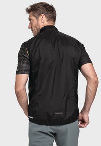 Schwarze Radjacke mit sleekem Design, kurzen bedruckten Ärmeln und einem Reißverschlusskragen. Hergestellt aus leichtem, windabweisendem Material.