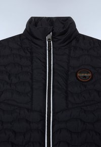 Černá zipová bunda s vysokým límcem, prošívanou texturou a kulatou nášivkou s oranžovými detaily. Úzký bílý přední zip.