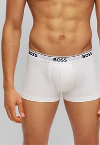 Boxers en coton blanc avec une ceinture logo noir et blanc, présentant un design ajusté et une texture lisse.