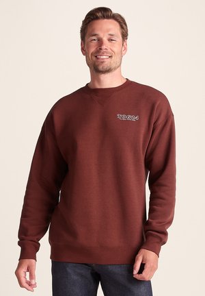 Maroon sweatshirt made of soft fabric, featuring a ribbed crew neckline, dropped shoulders, and a small embroidered logo on the chest.