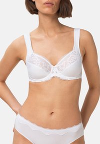 Biały biustonosz z fiszbinami, wykończony koronką, z kwiatowymi wzorami na miseczkach oraz szerokimi, regulowanymi ramiączkami. Gładka tkanina o klasycznym kroju.