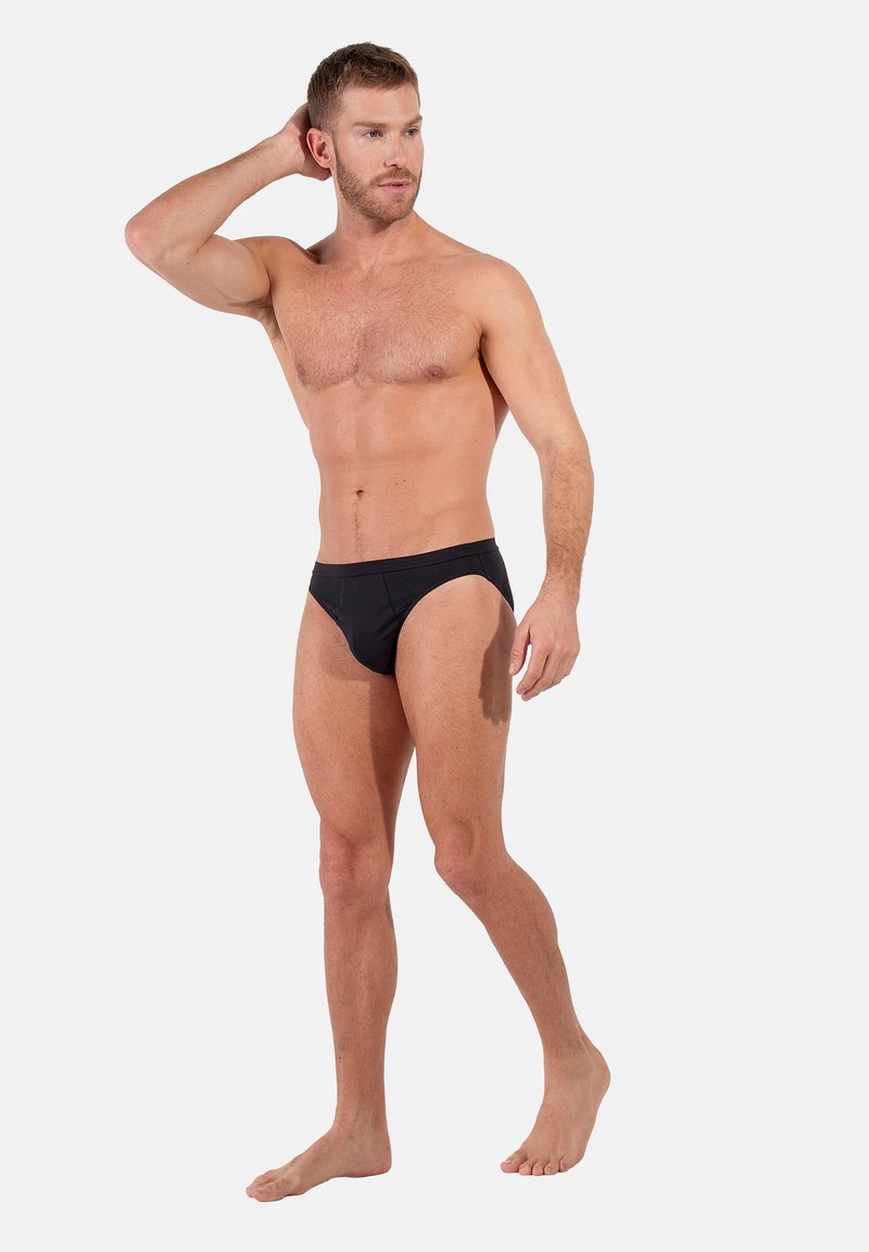 Bañador negro hecho de una tela suave y elástica. Cuenta con un diseño de tiro bajo, con un frente sin costuras y una cobertura lateral mínima.