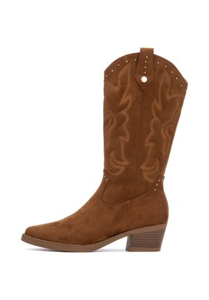 Bota de vaquero de ante marrón con puntera afilada, costuras decorativas y pequeños remaches en la parte superior. Tacón grueso y apilado para mayor estabilidad.