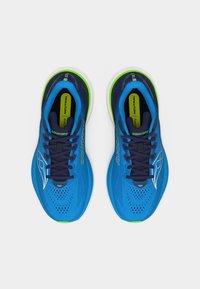 Ζευγάρι μπλε αθλητικά παπούτσια Saucony με μαύρα κορδόνια, λευκό λογότυπο, νεον πράσινες λεπτομέρειες και πάτους "Neutral", άνω όψη σε λευκό φόντο.