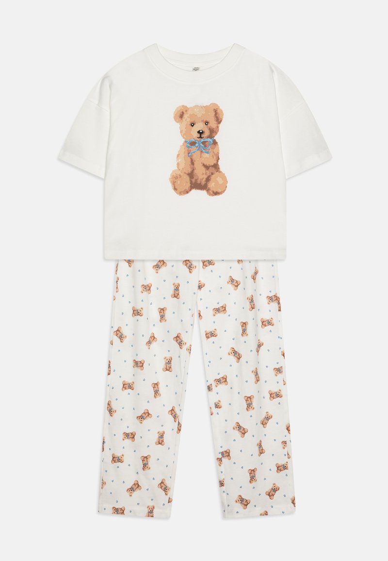 Ensemble de pyjama en coton blanc comprenant un haut à manches courtes avec un graphique d'ours en peluche et un pantalon à motifs avec de petites illustrations d'ours en peluche.