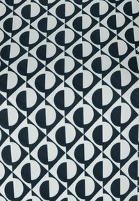 Gemusterter Stoff mit abwechselnden geometrischen Formen – schwarze Kreise und Dreiecke auf weißem Hintergrund; strukturierte, glatte Oberfläche.
