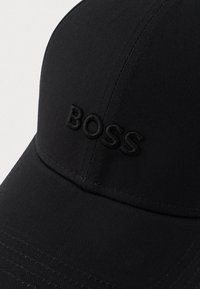 Fekete baseball sapka ívelt karimával, amelyen kiemelt fekete hímzett "BOSS" logó található az elülső panelen.