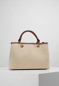 Bežová látková kabelka s herringbone vzorem, hnědými koženými detaily, zlatými kovovými prvky a dvojitými horními uchy. Obdélníkový tvar s plochým dnem.