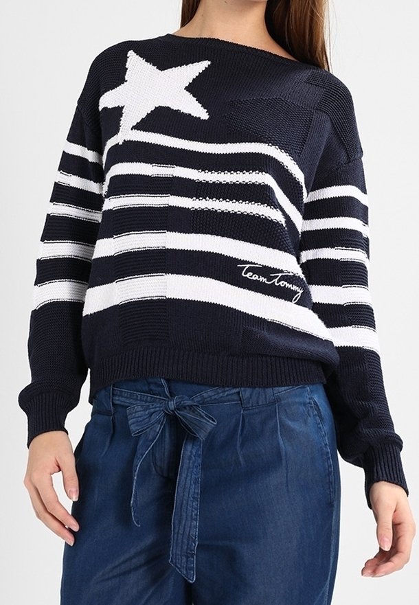 Pull en tricot bleu marine avec des rayures horizontales blanches et un motif d'étoiles ; présente une broderie "Team Tommy" à l'avant.