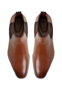 Botas Chelsea de cuero marrón con un acabado suave, Punta puntiaguda, paneles elásticos en los laterales y una pequeña asa para facilitar el calce.