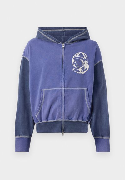 Fialová zipová mikina s grafickým motívom astronauta, s kontrastnými tmavými rukávmi, s kapucňou na šnúrku a prednými vreckami.