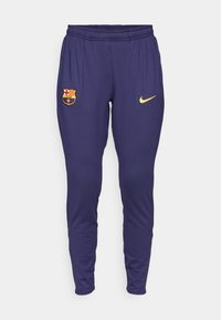 Pantalons de sport navy avec une taille élastique, ornés d'un logo Nike jaune et d'un blason multicolore du FC Barcelone sur la cuisse gauche.