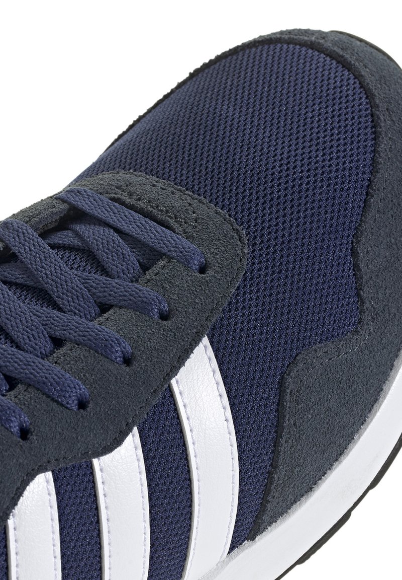 Marineblaue Sportschuhe mit einem oberen Teil aus Mesh, suede Akzenten und drei weißen Streifen. Sie haben runde Schnürsenkel und eine gepolsterte Laufsohle.