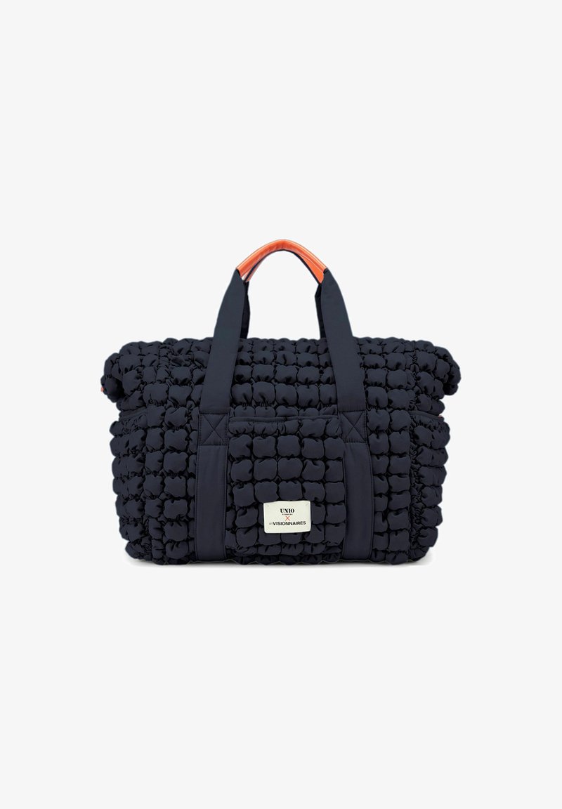 Sac fourre-tout matelassé marine avec une poignée d'accent orange, comportant une poche frontale et un patch logo, fabriqué en tissu texturé et rembourré.