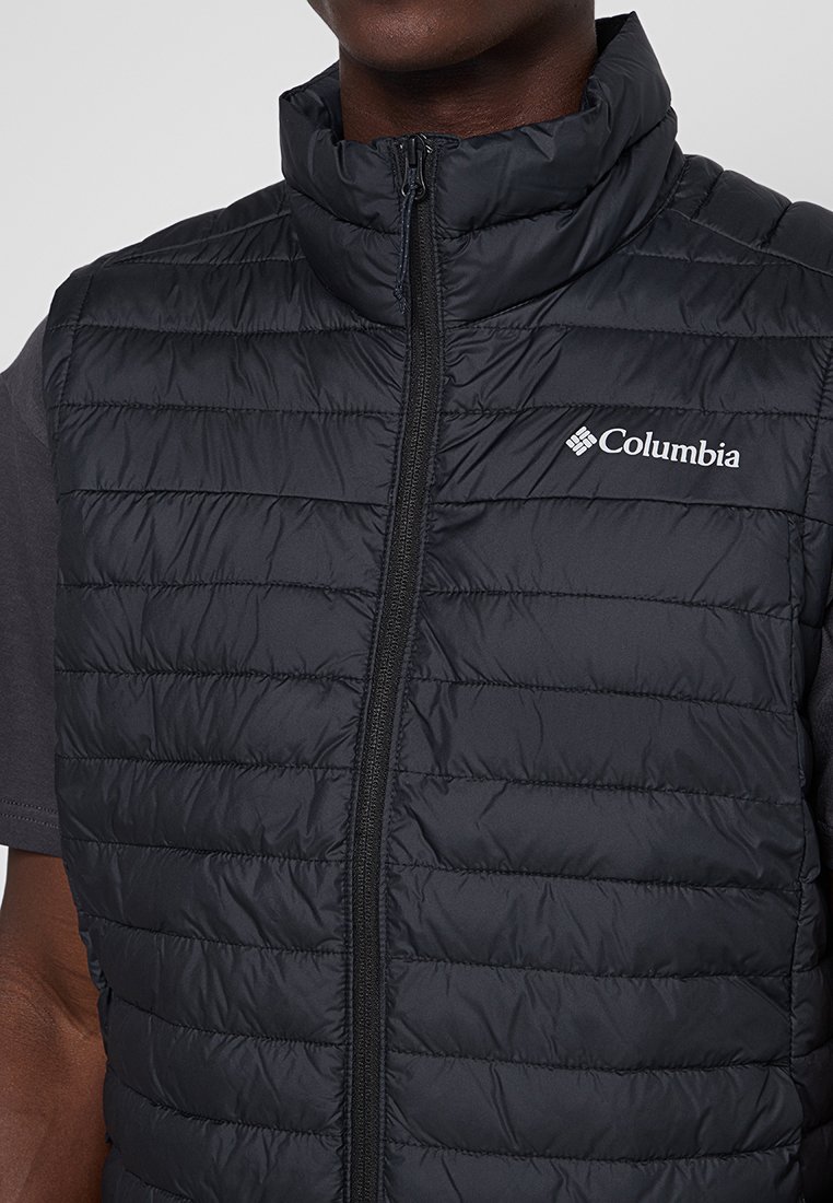 Gilet imbottito nero con colletto alto, chiusura con zip e logo Columbia sul petto sinistro. La trama è liscia con cuciture orizzontali.