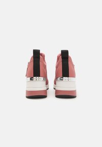 Pantofi sport roz cu un superior din țesătură texturată, accente negre, o placa de călcâi argintie și o talpă intermediară albă în contrast.
