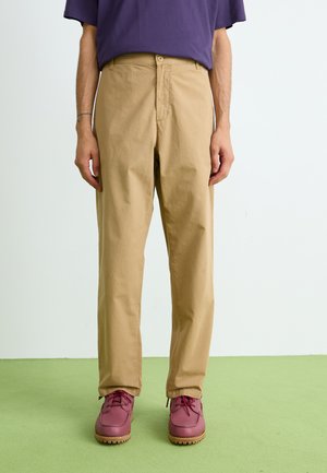 Chino khaki con design a gamba dritta, realizzati in un tessuto resistente. Presentano tasche frontali e chiusura con bottone, abbinati a scarpe bordeaux.