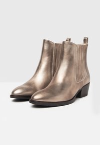 Bottines en bronze métallisé avec un petit talon bloc, des panneaux latéraux élastiques et des tirants ; texture lisse avec une silhouette élégante et épurée.