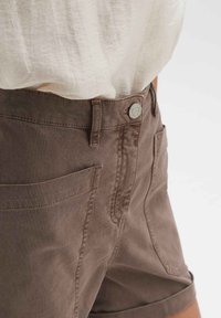 Bruine katoenen shorts met een knoopsluiting, vijf zakken en opgerolde manchetten. De stof heeft een soepele textuur met subtiele stikseldetails.