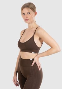 Brun ribbet bralette og højtaljede leggings med tynde stropper og en glat tekstur. Etiketter på linningen og kanten.