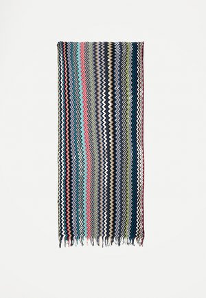 Pravokotni šal z vertikalnimi cikcak črtami v modri, rdeči, beli, zeleni in črni barvi, z robovi z resicami na dnu.