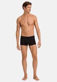 Zwarte boxershorts met een effen ontwerp, een elastische tailleband en een strakke pasvorm. Het materiaal lijkt glad en rekbaar.