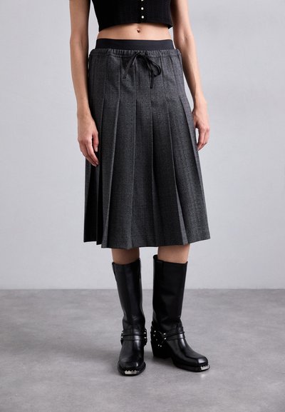 Gray plaid pleated skirt with a black elastic waistband and drawstring, paired with knee-high black boots featuring metal accents.