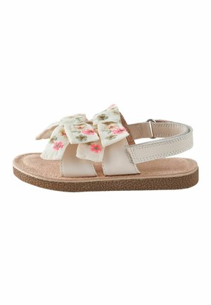 Child’s beige sandal with a cushioned sole, adjustable strap, and fabric bows adorned with pink and green floral embroidery.