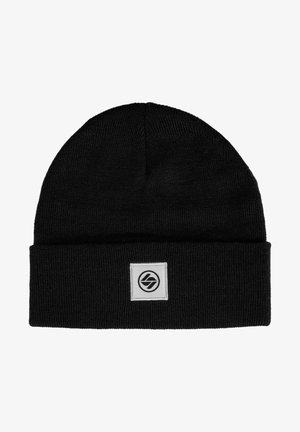 Schwarze Beanie-Mütze aus geripptem Strickstoff, mit umgeschlagenem Saum und einem quadratischen Logo-Patch in Weiß mit einem kreisförmigen Design.